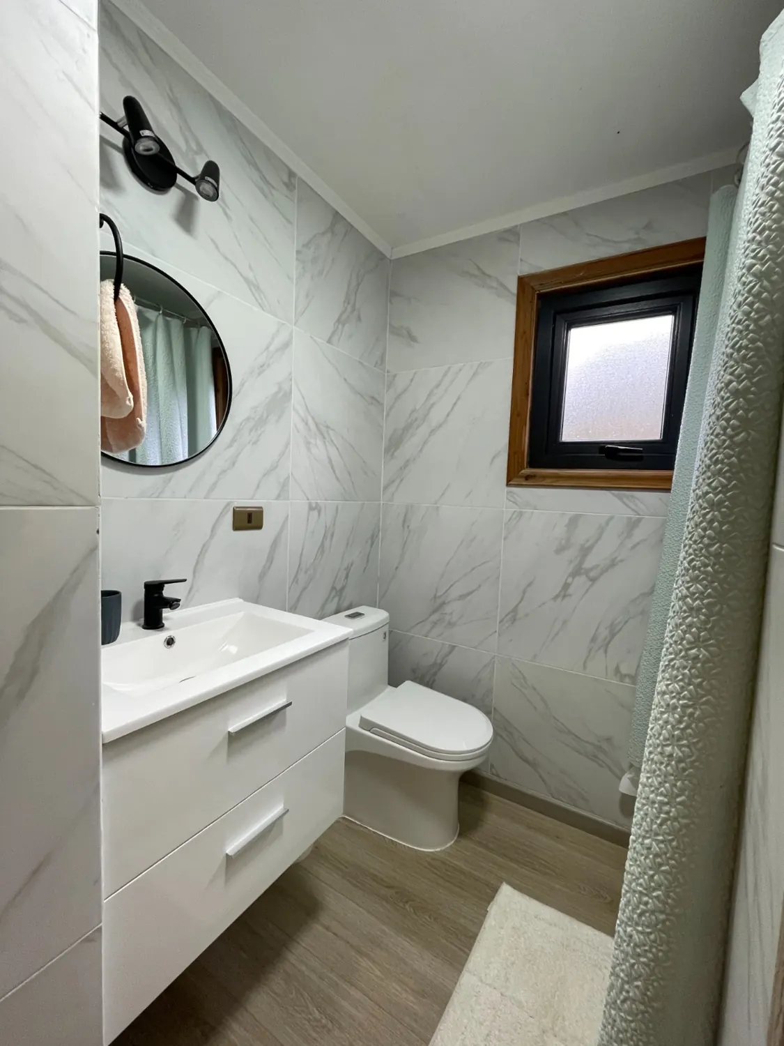 Baño moderno con mármol claro y lavamanos blanco